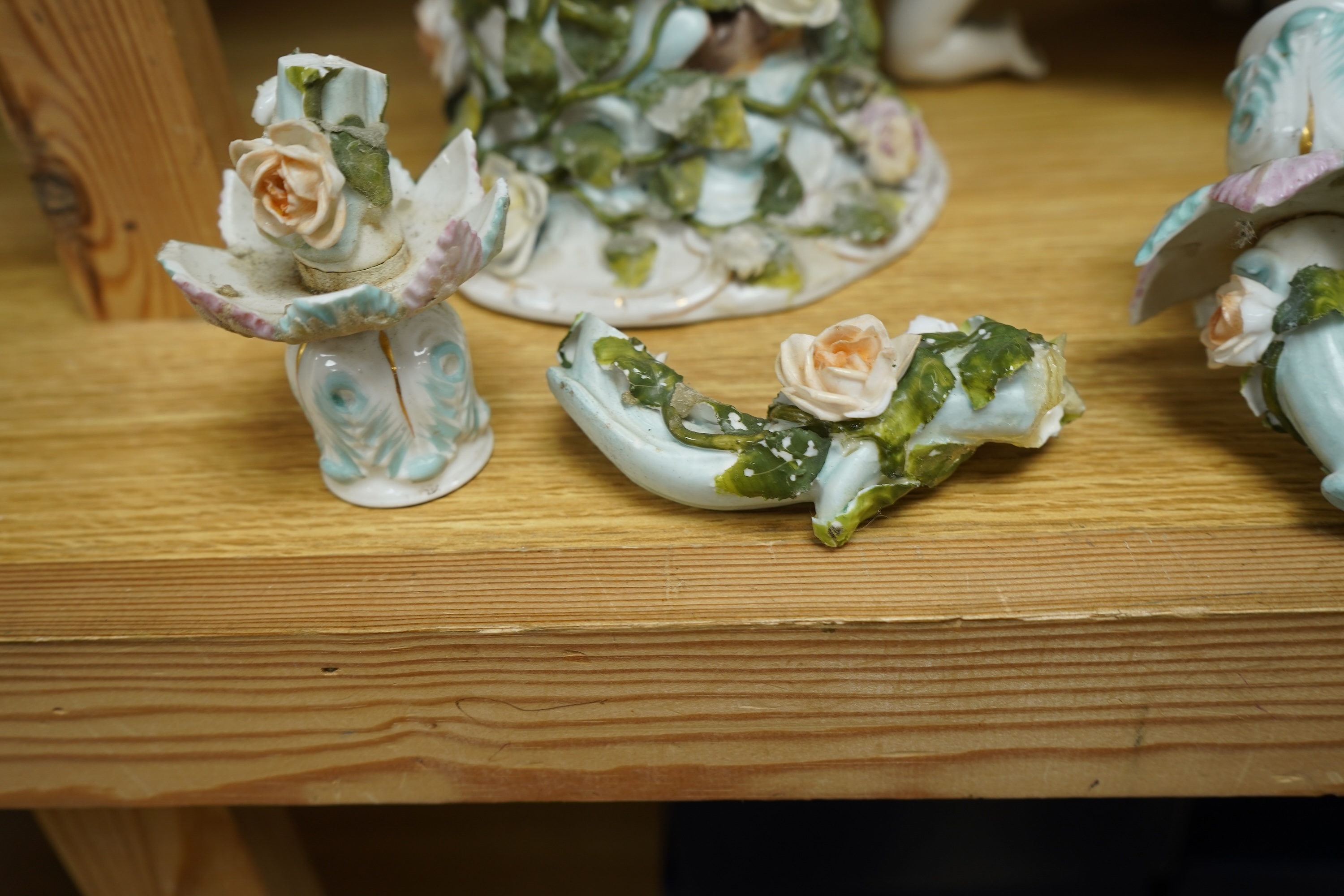 A German flower encrusted porcelain figural candelabrum, 30cm high, a cherub jardiniere and a cherub vase, all encrusted